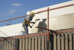 Builder worker painting facade of high-rise building