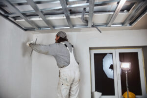 Workman plastering gypsum walls inside the house.
