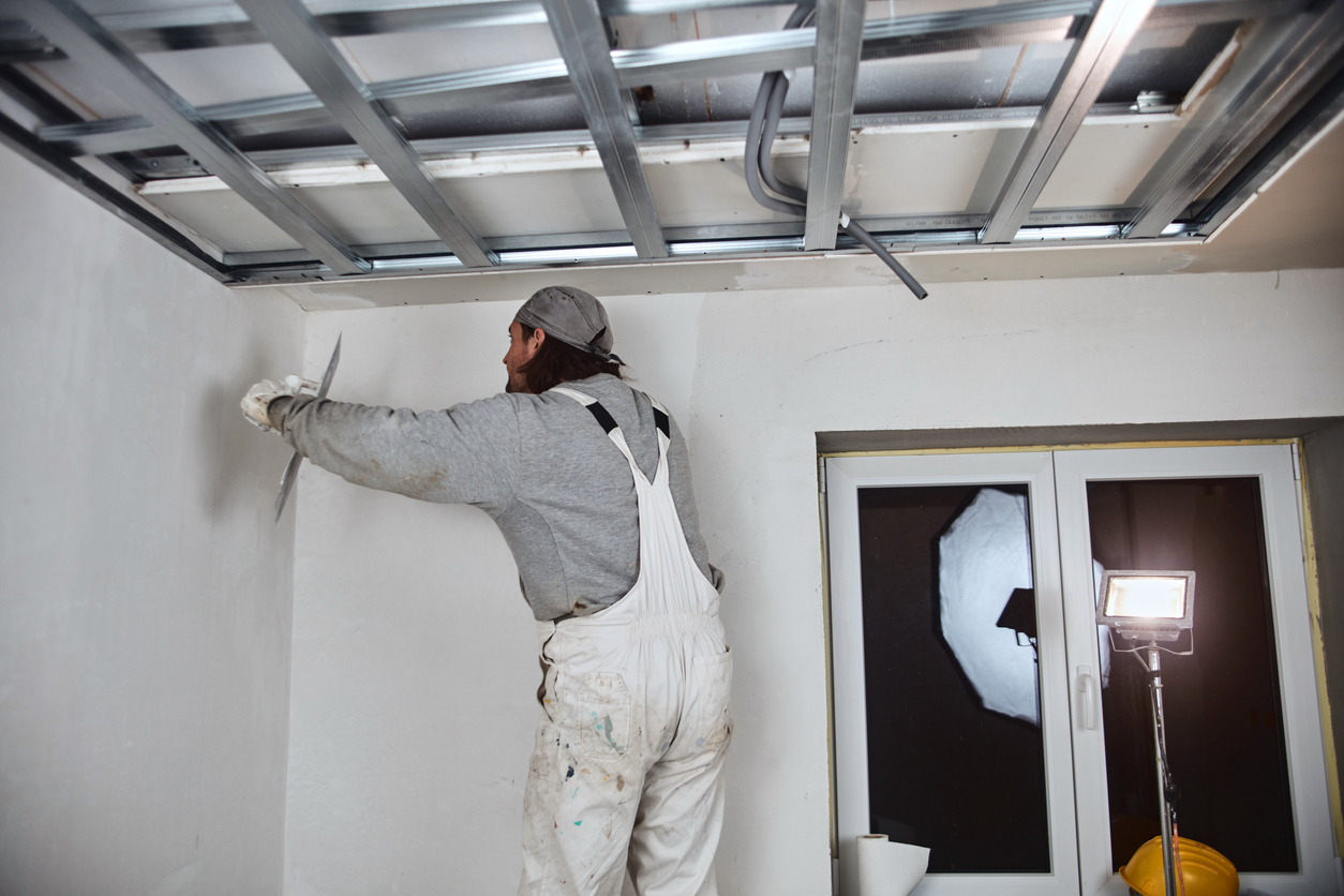 Workman plastering gypsum walls inside the house.