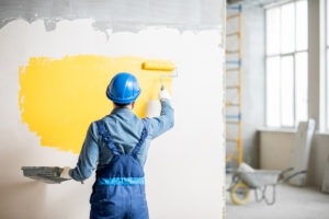 Workamn painting wall indoors