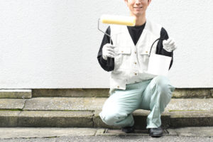 man in apron holding paintbrush and bucket outdoors