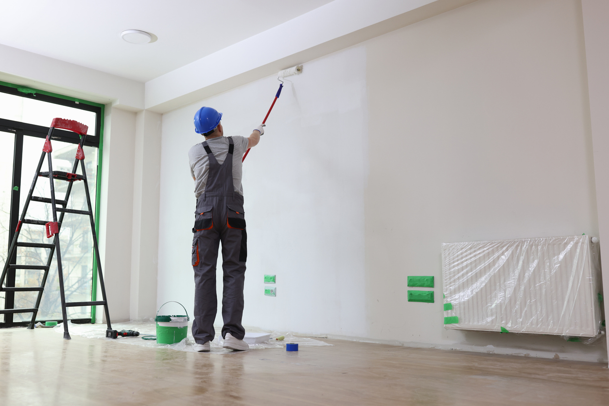 Professional painter paints office wall with roller brush