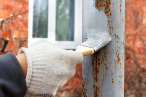 Gloved hand painting primer anti rust on steel poles for construction