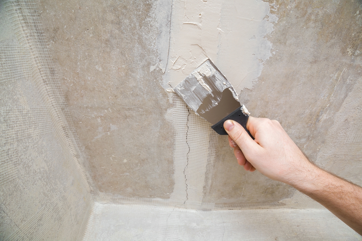 Worker hands using spatula and plastering ceiling