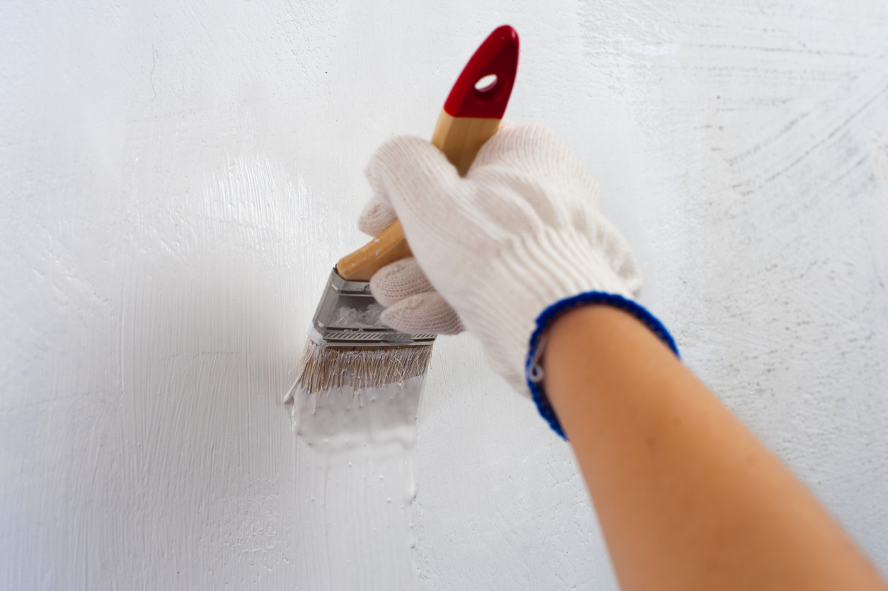 Female hand holding paintbrush with white color